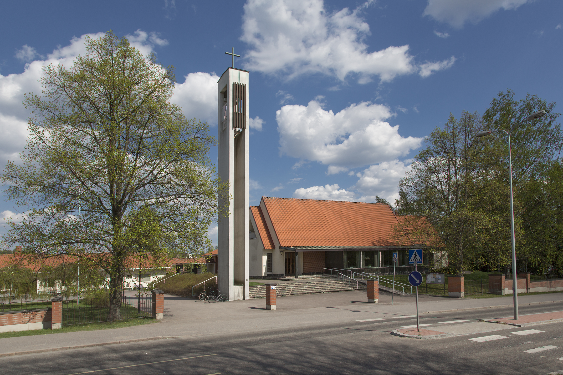 Kuvassa on Launeen kirkko alkukesästä. Vasemmalla on kellotorni ja sen vieressä kirkkorakennus.