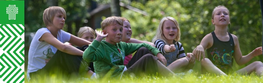 Lapset istuvat iloisina vihreällä nurmella.