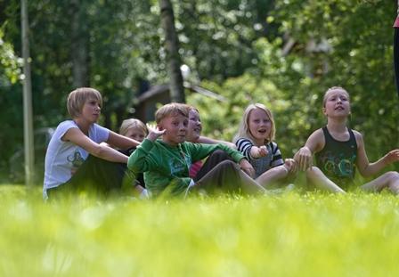 Valokuvassa lapset istuvat vihreällä nurmella.
