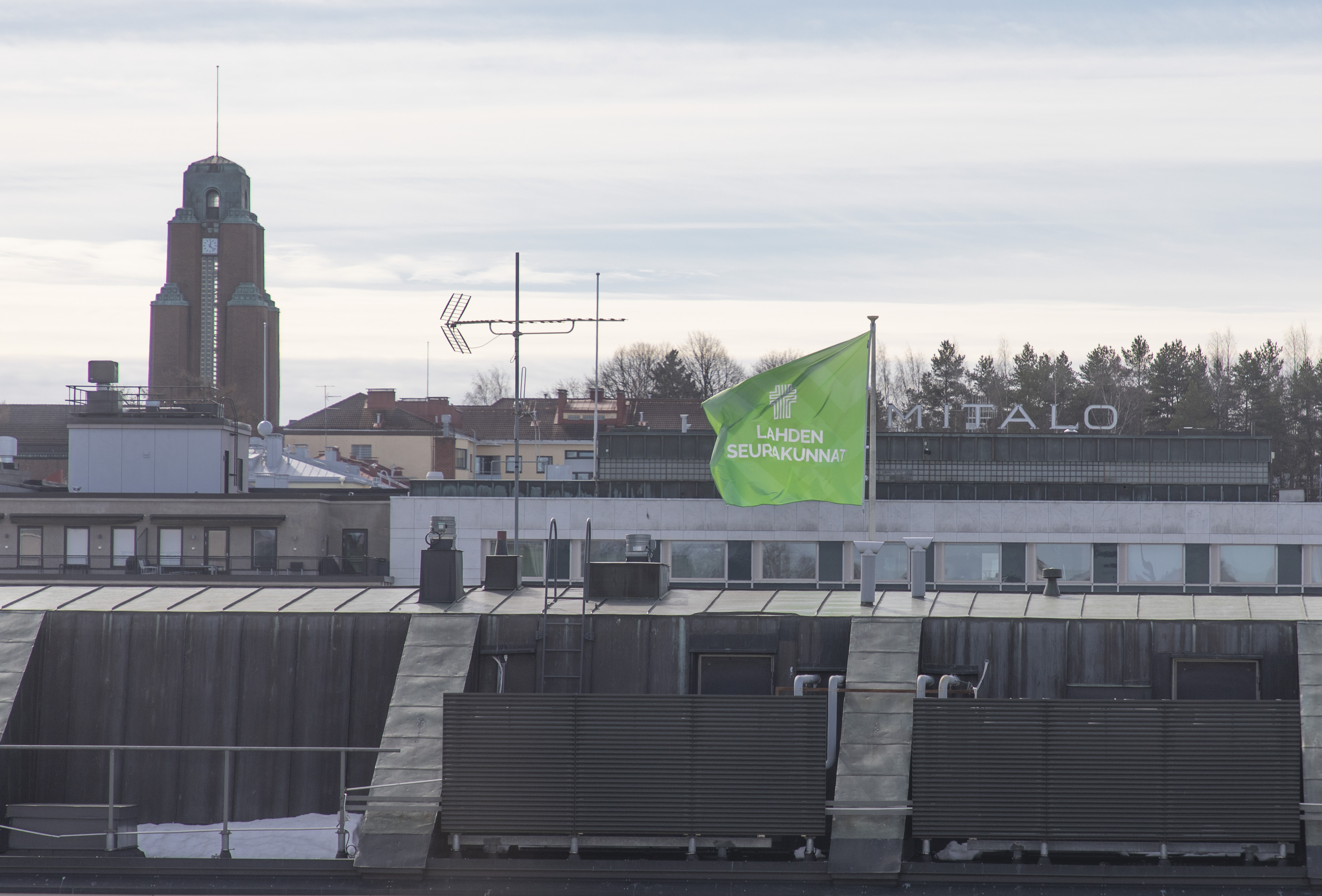 Kuvassa on yrityslippu, joka liehuu Vapaudenkatu 6:n katolla.