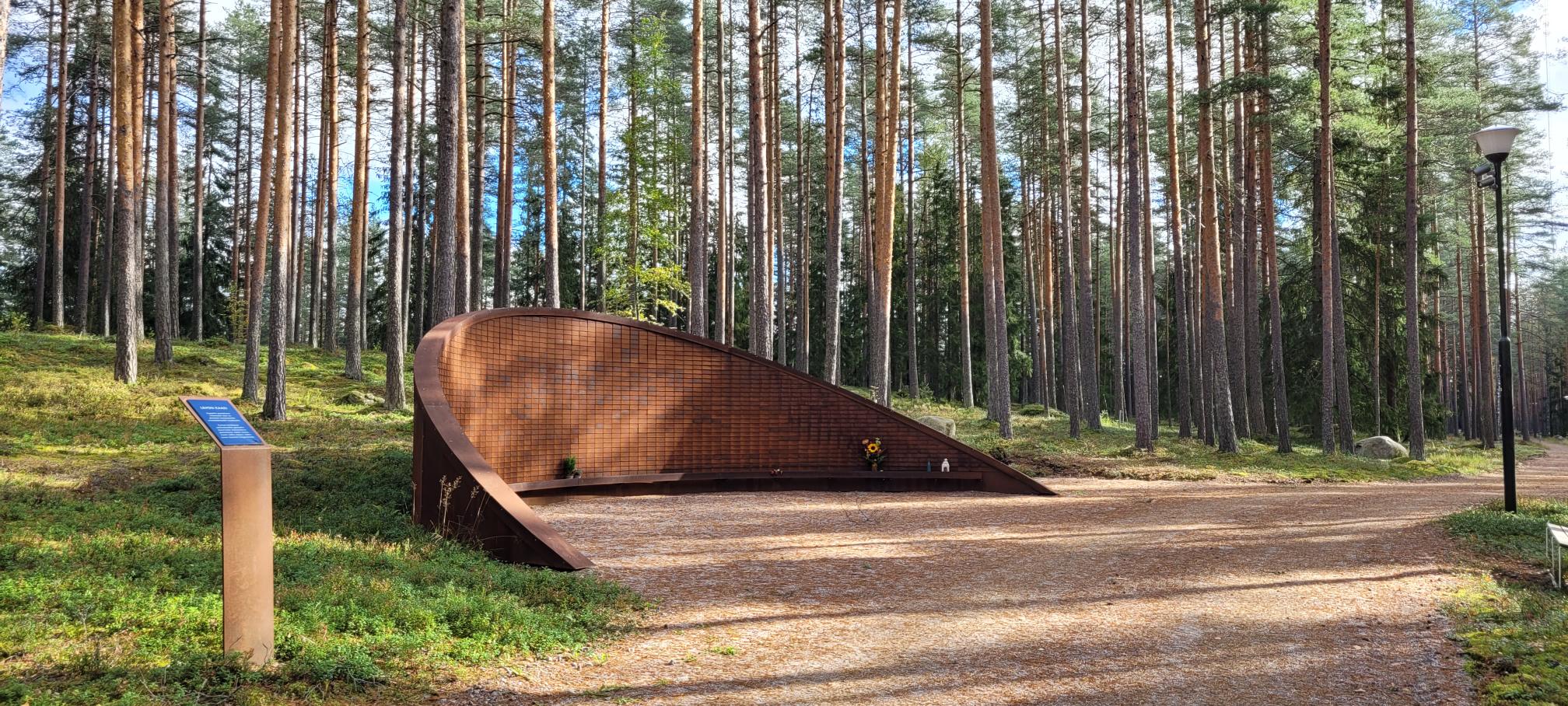 Cortenteräksinen yhteishautamuistomerkki. Taustalla mäntymetsää.