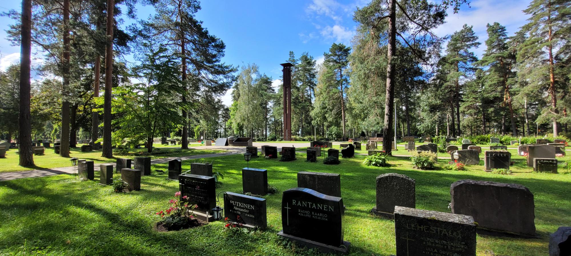Hautamuistomerkkejä nurmikolla, taustalla näkyy kellotapuli.